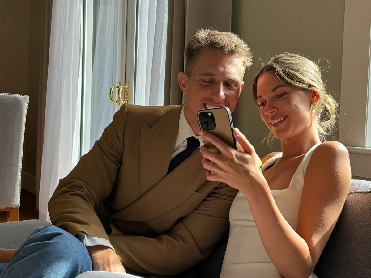 An engaged couple on a sofa, booking on a phone