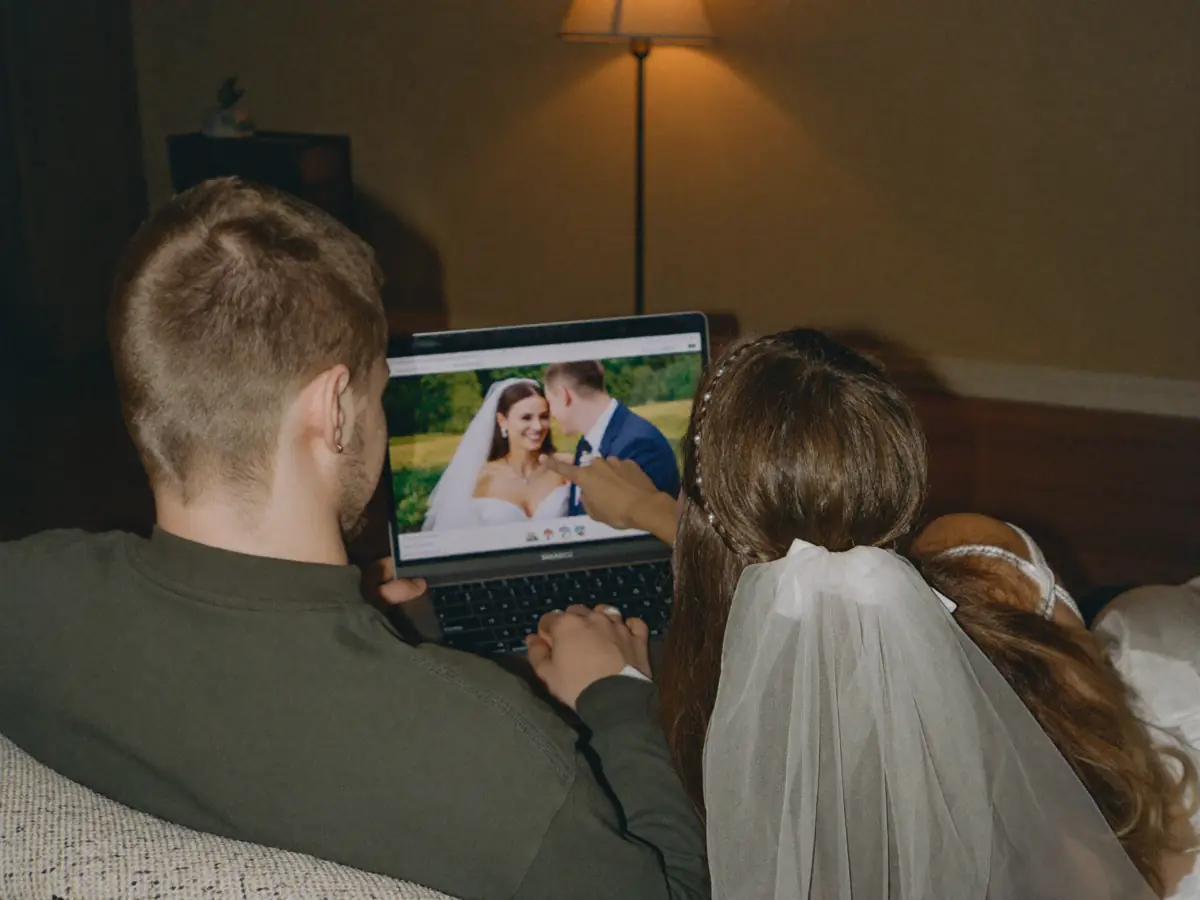 A newly married couple watching their wedding film on a laptop