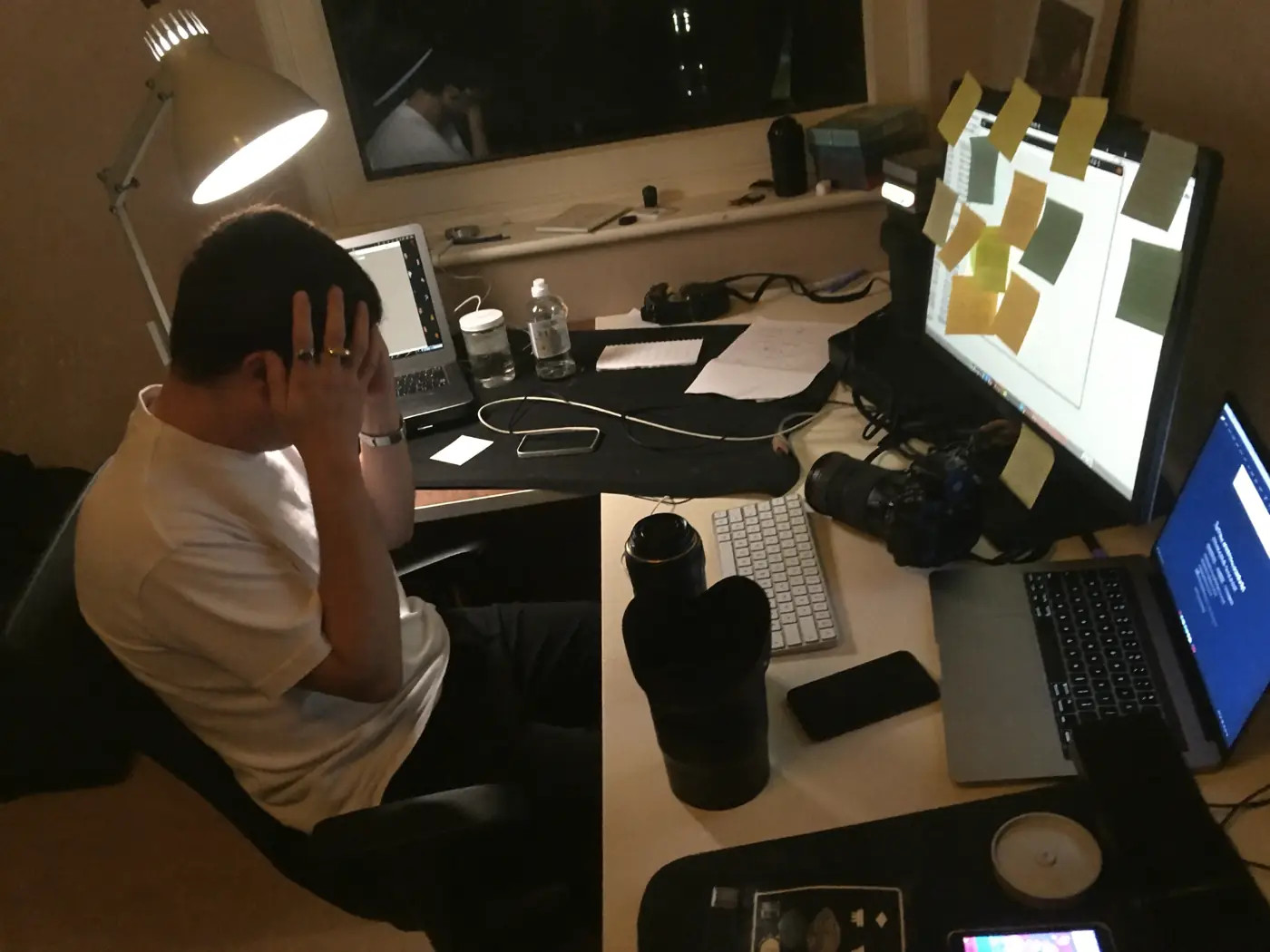 A studio owner with head in hand at a desk covered in sticky notes