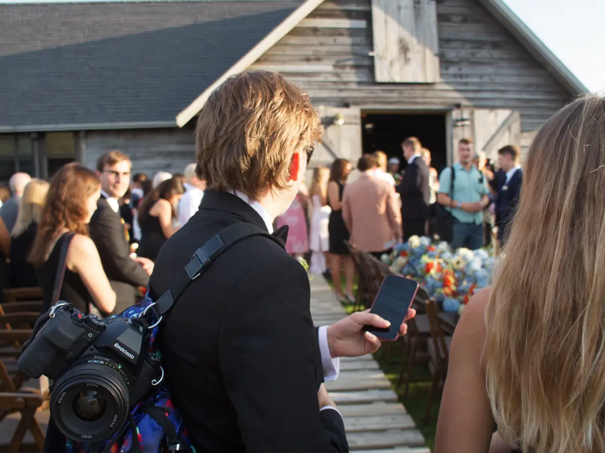 A second shooter with a camera arriving at a barn wedding