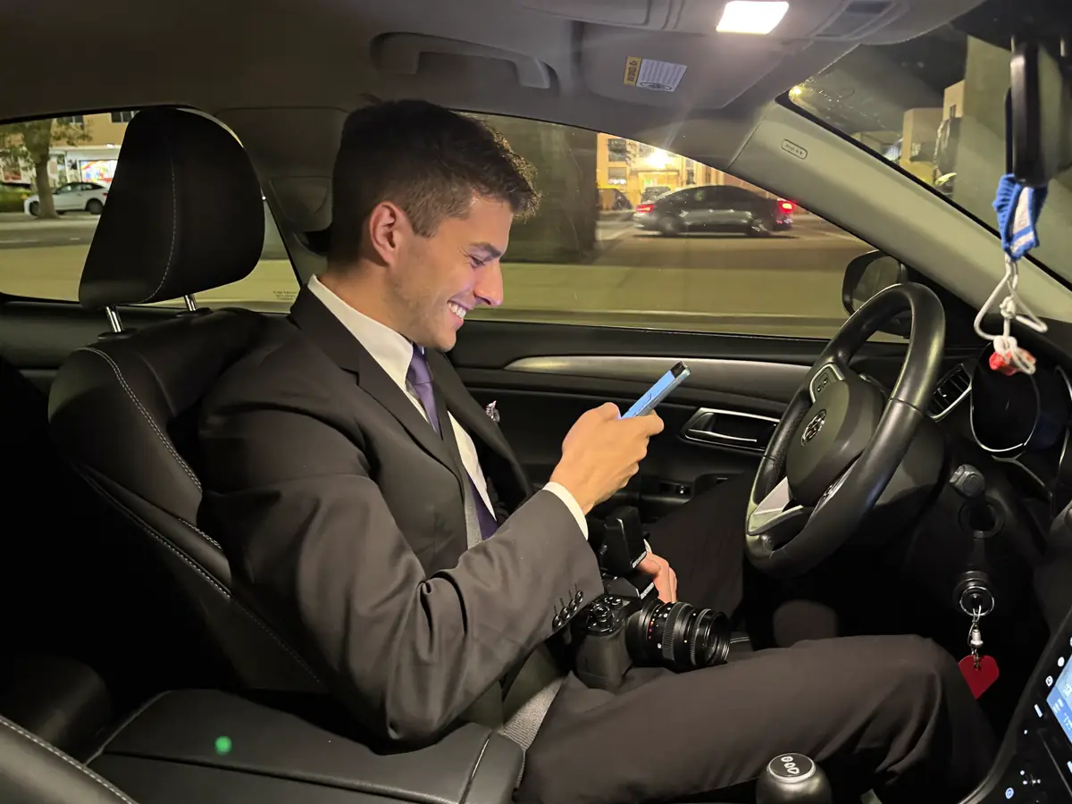 A second shooter smiling at his phone in his car
